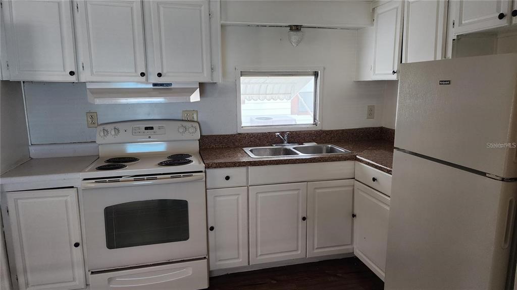 A kitchen features white cabinets, a white stove, a double sink, and a white refrigerator — 196 SUNSET DRIVE, LAKE ALFRED, FL