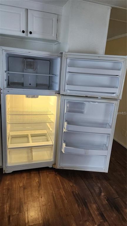 An open white refrigerator stands in a kitchen with wood-look flooring and white cabinets — 196 SUNSET DRIVE, LAKE ALFRED, FL