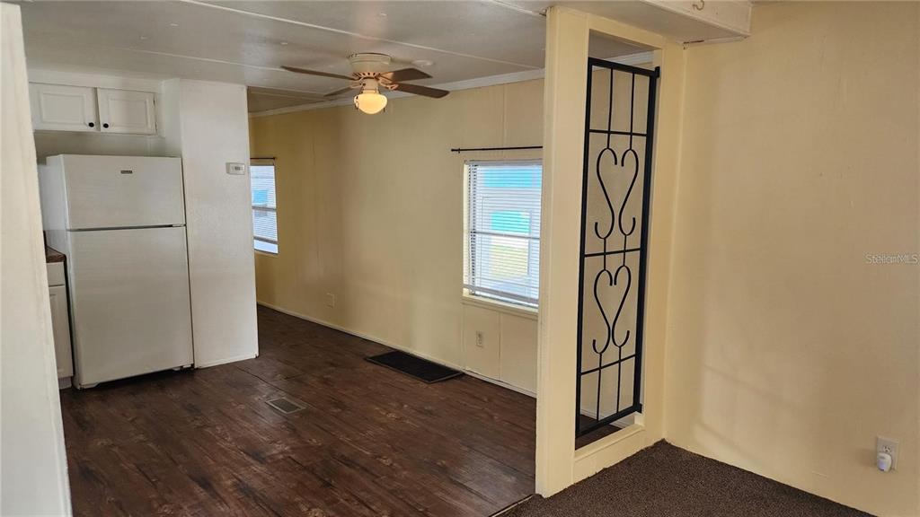 A kitchen and living area featuring wood-look flooring, a white refrigerator, and a decorative screen — 196 SUNSET DRIVE, LAKE ALFRED, FL