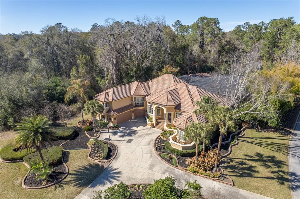 An aerial view of a large tan house with a tile roof and circular driveway — 695 SE 47TH LOOP, OCALA, FL