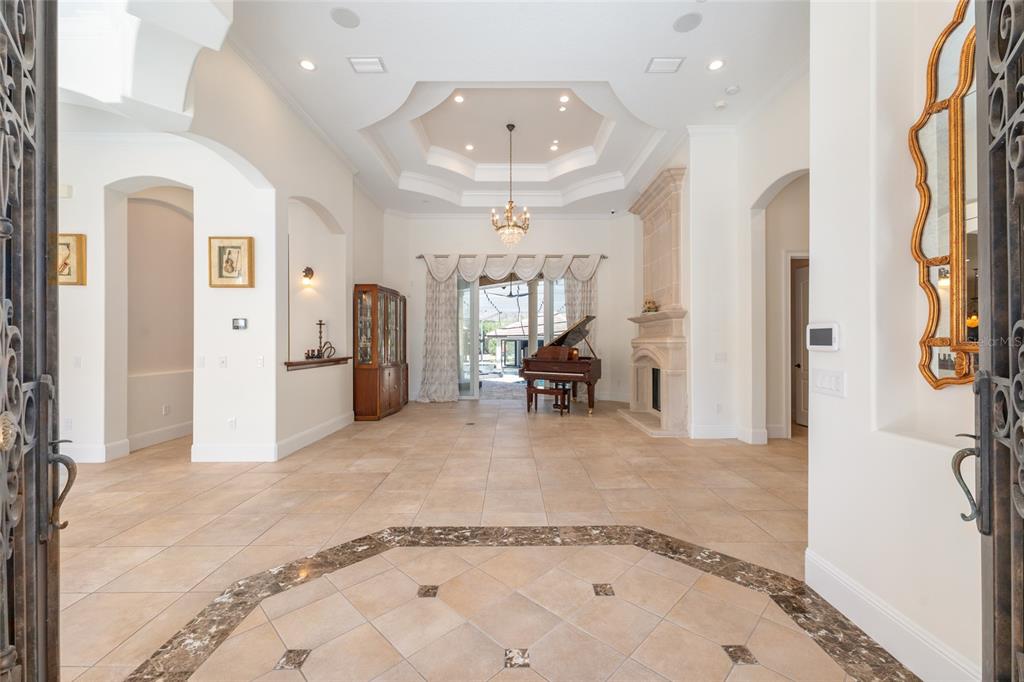 A grand foyer with tile flooring leads to a living area featuring a grand piano — 695 SE 47TH LOOP, OCALA, FL