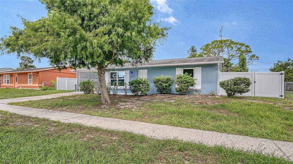 A single-story blue house with a white fence and a large tree in the front yard — 4341 GORGAS, NORTH PORT, FL