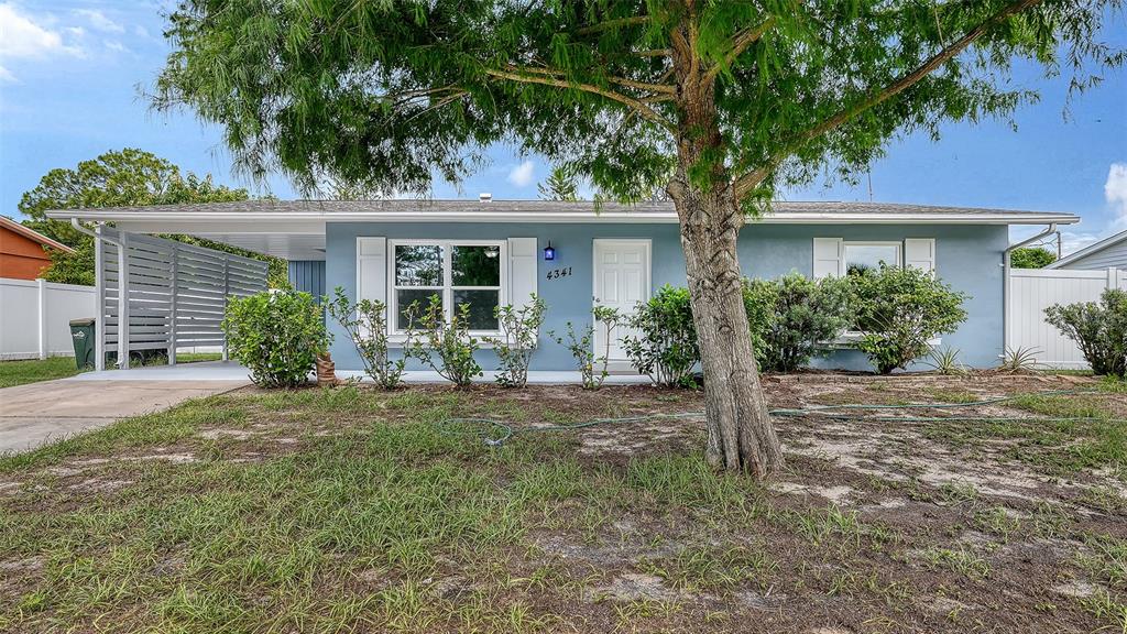 A single-story light blue house features a front carport, white shutters, and a large tree — 4341 GORGAS, NORTH PORT, FL