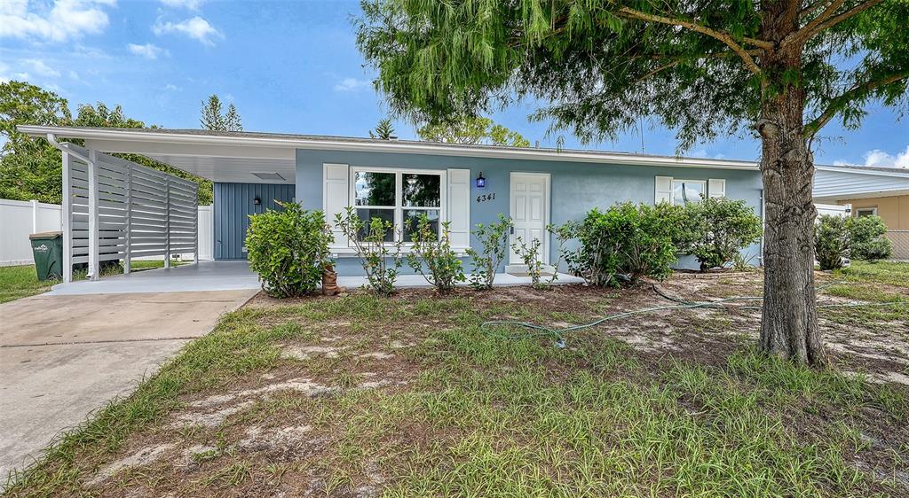 A single-story blue house features a carport, white shutters, and a large tree in front — 4341 GORGAS, NORTH PORT, FL