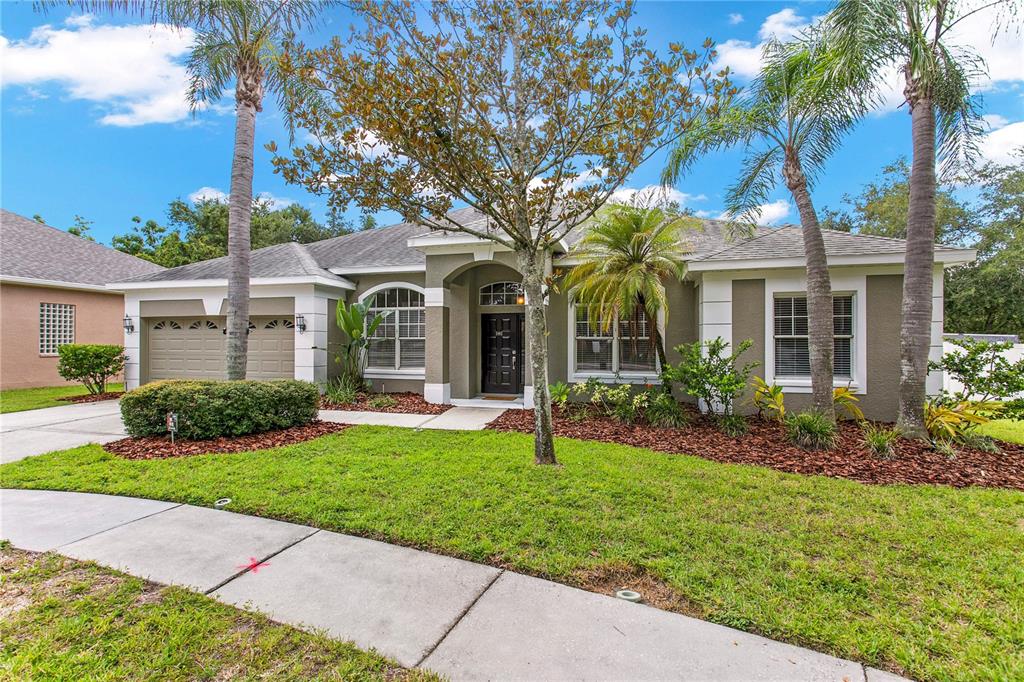 A single-story suburban house with a two-car garage, palm trees, and a landscaped front yard — 1604 LORIANA STREET, BRANDON, FL