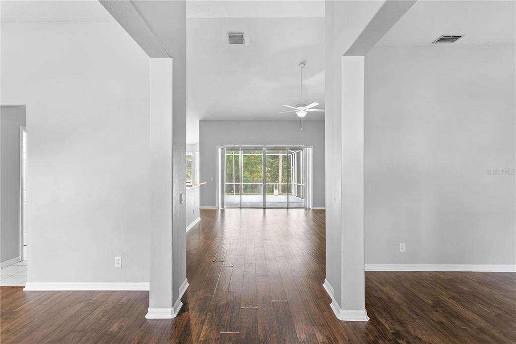 A view through a wide entryway into a living area with wood-look flooring and sliders — 1604 LORIANA STREET, BRANDON, FL