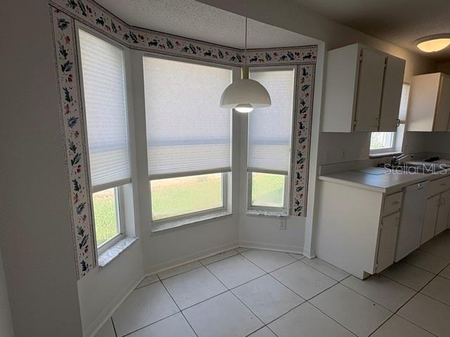 A kitchen breakfast nook features a bay window with pleated shades and white tile flooring — 505 CEDAREDGE DRIVE, NEW SMYRNA BEACH, FL