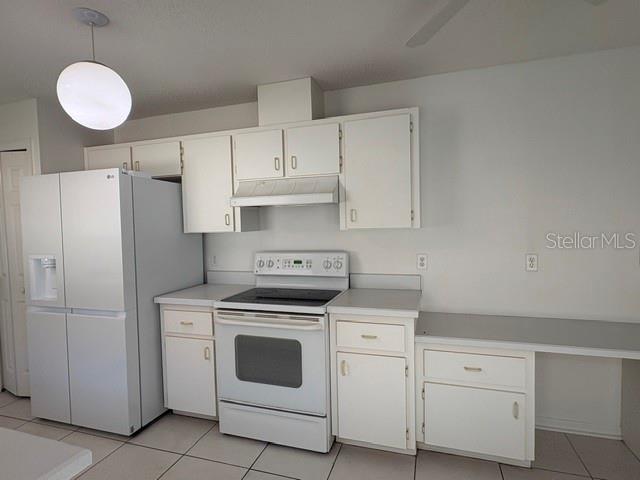 A kitchen featuring white cabinets, a white refrigerator, a white stove, and light-colored tile flooring — 505 CEDAREDGE DRIVE, NEW SMYRNA BEACH, FL