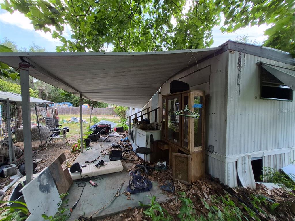 An exterior view shows a mobile home with a covered patio area containing cluttered items — 11366 SE 40TH AVENUE, BELLEVIEW, FL