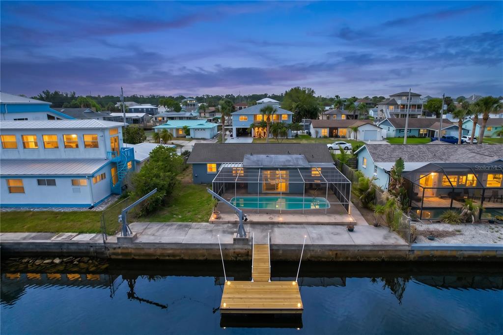 An aerial view of a waterfront house featuring a swimming pool, screened lanai, and dock — 7513 HATTERAS DRIVE, HUDSON, FL