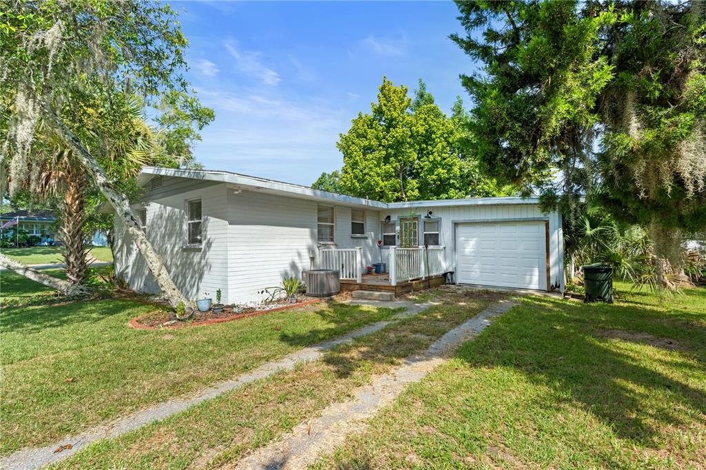 A single-story white house with a garage, a wooden deck, and a grassy front yard — 553 S LANVALE AVENUE, DAYTONA BEACH, FL