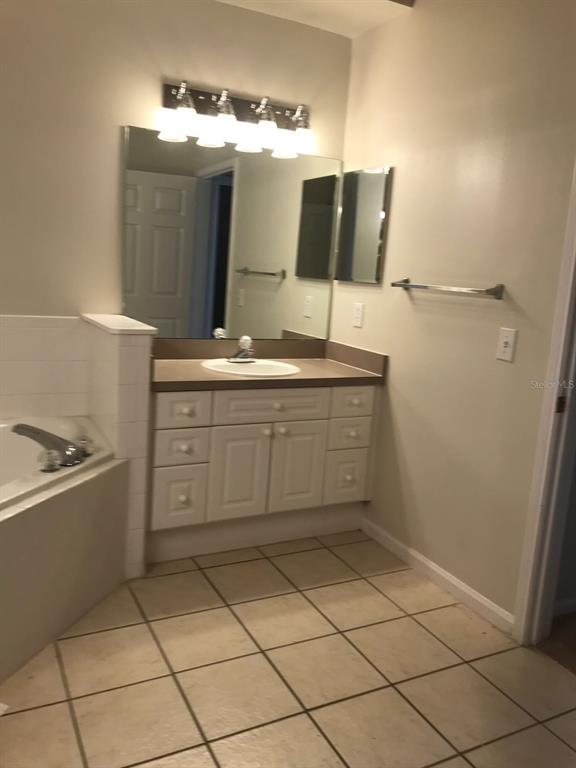 A bathroom features a white vanity with a sink, a mirror, and a tiled floor — 239 LONGVIEW AVENUE UNIT 201, CELEBRATION, FL