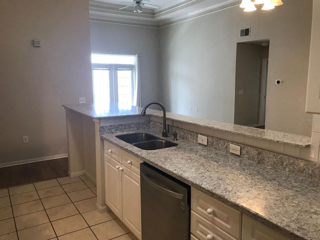 A kitchen features white cabinets, granite countertops, a stainless steel dishwasher, and a double sink — 239 LONGVIEW AVENUE UNIT 201, CELEBRATION, FL