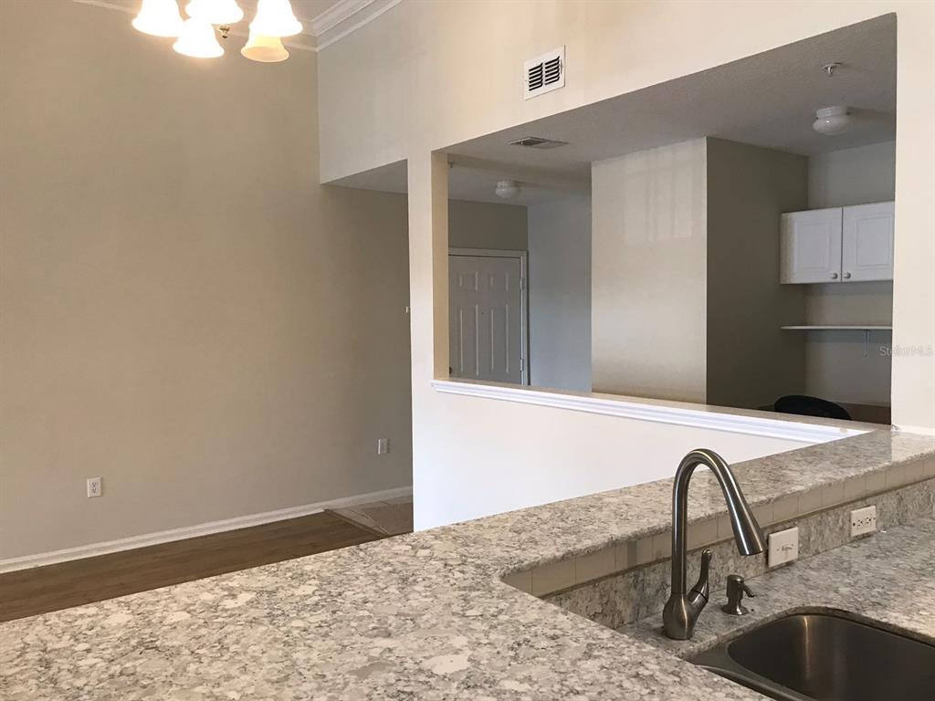 A kitchen with granite countertops and a sink overlooks an adjacent living area — 239 LONGVIEW AVENUE UNIT 201, CELEBRATION, FL