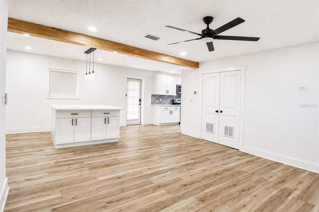 A bright kitchen and dining area features white cabinets, a central island, and wood flooring — 113 INWOOD CIRCLE, BRANDON, FL