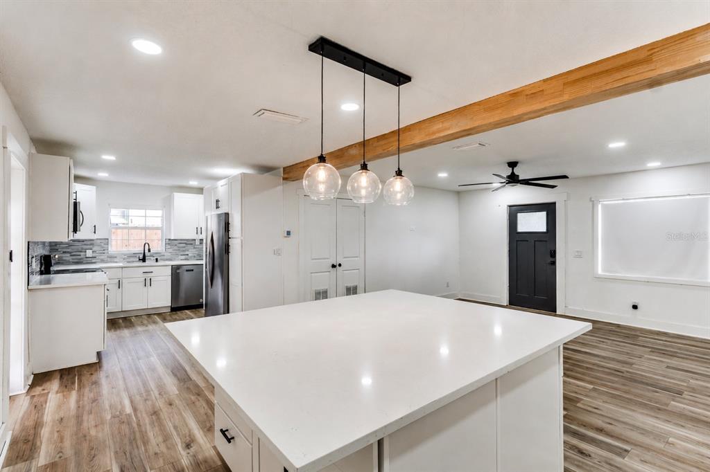 A kitchen with a white island, pendant lighting, wood-look flooring, and a black exterior door — 113 INWOOD CIRCLE, BRANDON, FL