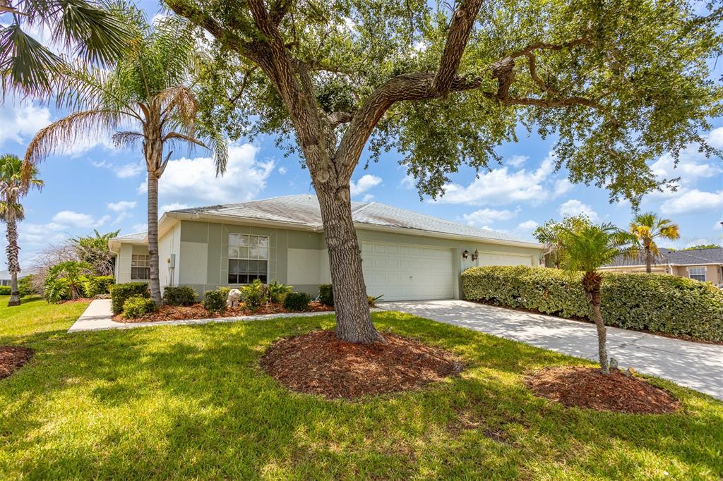 A single-story house with a two-car garage, a large oak tree, and palm trees — 29312 MARKER LOOP, SAN ANTONIO, FL