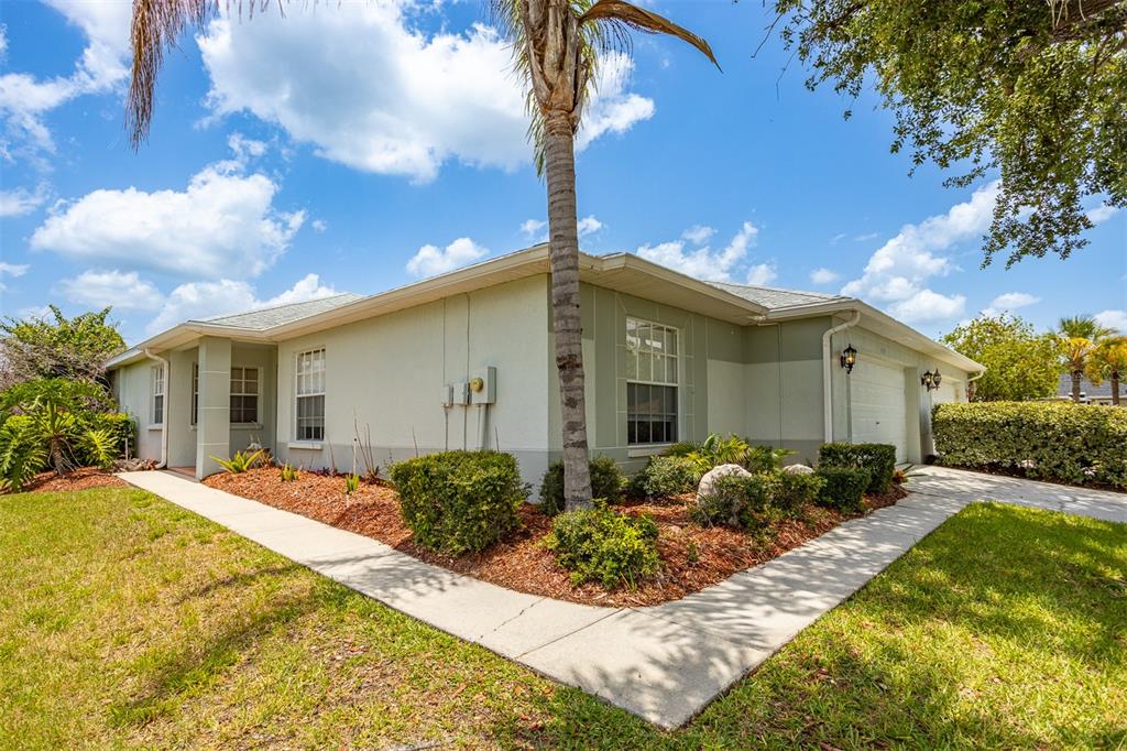 A single-story house with light-colored stucco walls, a palm tree, and a concrete walkway — 29312 MARKER LOOP, SAN ANTONIO, FL