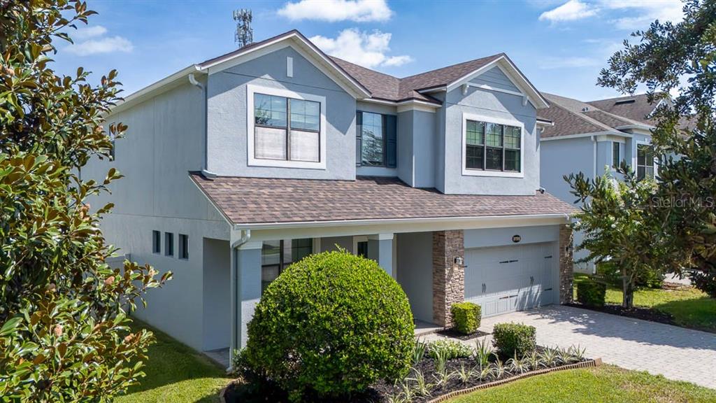 A two-story house with light blue stucco siding, a stone-accented garage, and a paved driveway — 5728 RUE GALILEE LANE, SANFORD, FL
