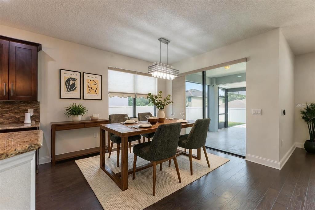 A dining room with a wooden table, dark chairs, and a sliding door to a patio — 5728 RUE GALILEE LANE, SANFORD, FL
