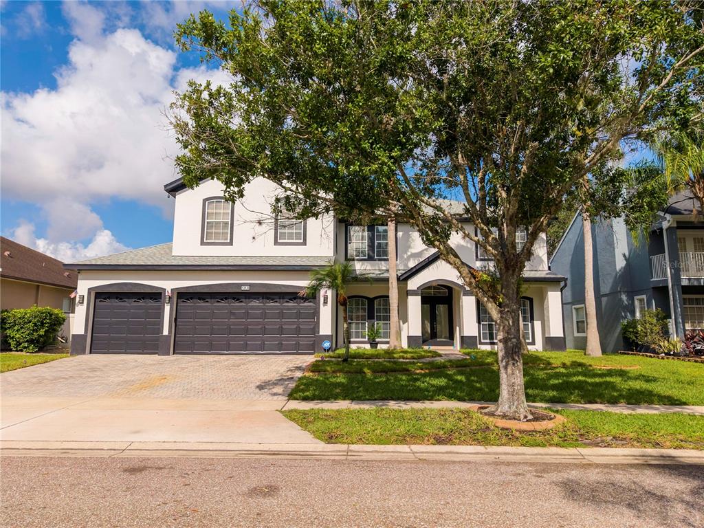 A two-story house with a three-car garage, white stucco exterior, and a large front tree — 13138 PALOMA DRIVE, ORLANDO, FL