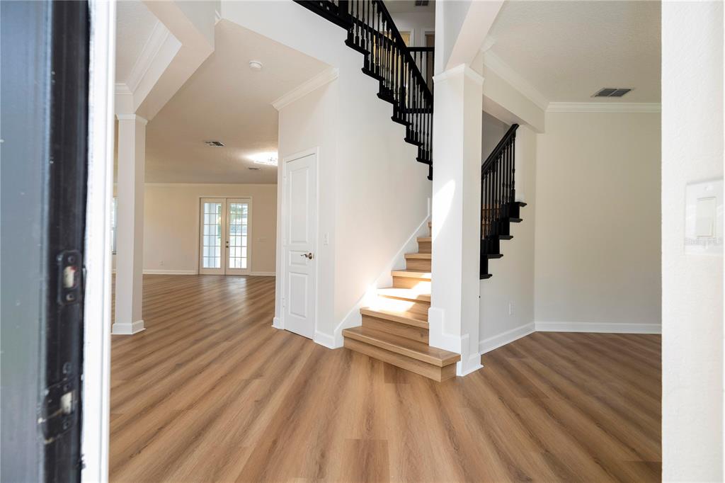 An entryway features light wood flooring, a white staircase with black railings, and open living space — 13138 PALOMA DRIVE, ORLANDO, FL