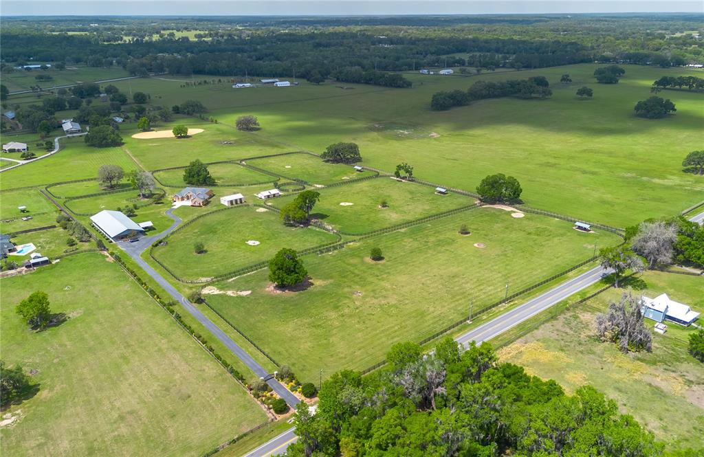 An aerial view shows a rural property with a house, barn, and fenced pastures — 12610 NW GAINESVILLE ROAD, REDDICK, FL