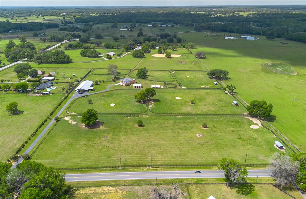 An aerial view shows a large rural property with a house, barn, and fenced pastures — 12610 NW GAINESVILLE ROAD, REDDICK, FL
