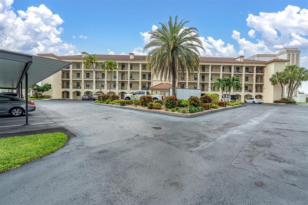 A stone sign labeled 26 Granada stands in front of a multi-story apartment building — 19029 US HIGHWAY 19 N UNIT 26-208, CLEARWATER, FL