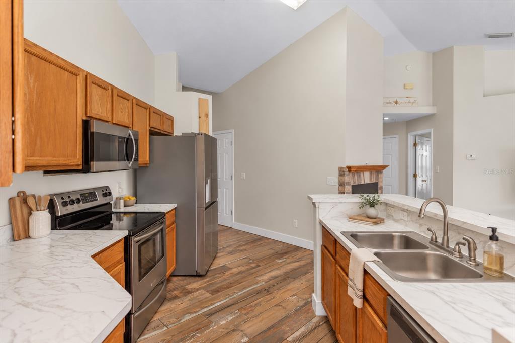 A kitchen with wood cabinets, stainless steel appliances, and white marble-look countertops — 1005 WHISPRING CREEK WAY, OSTEEN, FL