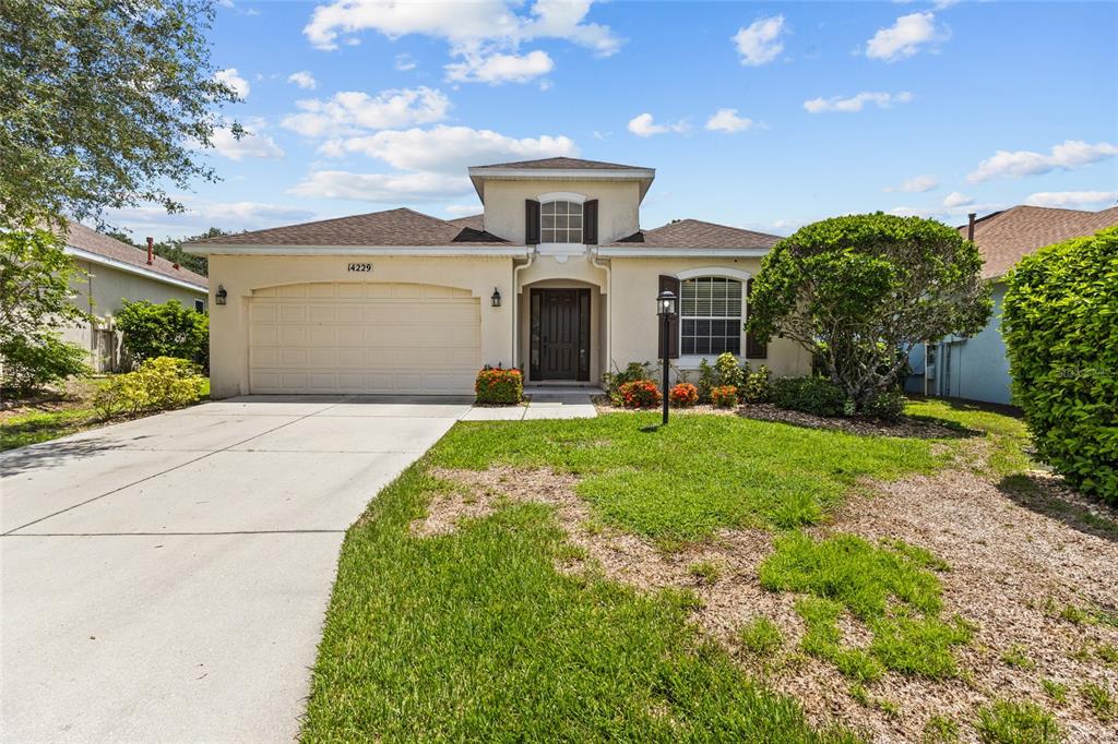 A tan single-story house with a two-car garage and a small front lawn — 14229 CATTLE EGRET PLACE, LAKEWOOD RANCH, FL