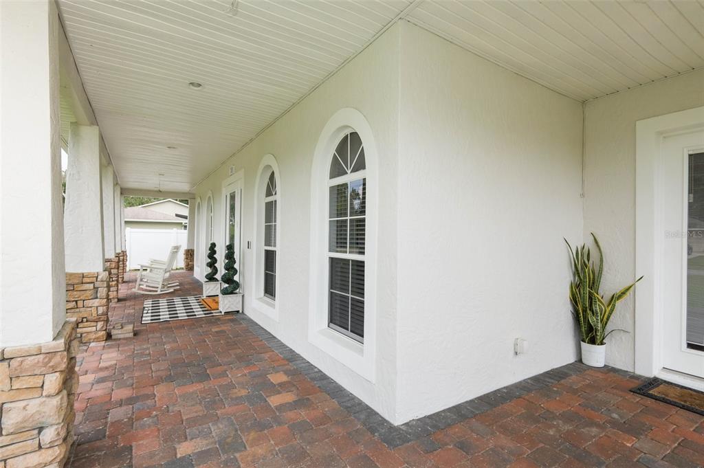 A covered brick patio features arched windows, white stucco walls, and a white front door — 787 FANTASY LANE, CHULUOTA, FL
