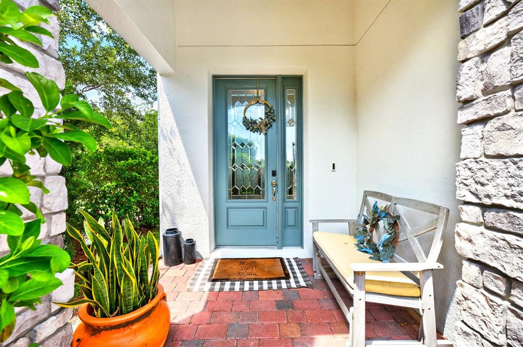 A front porch features a blue door, a wooden bench, and a potted snake plant — 8205 BAYLISS COURT, ORLANDO, FL