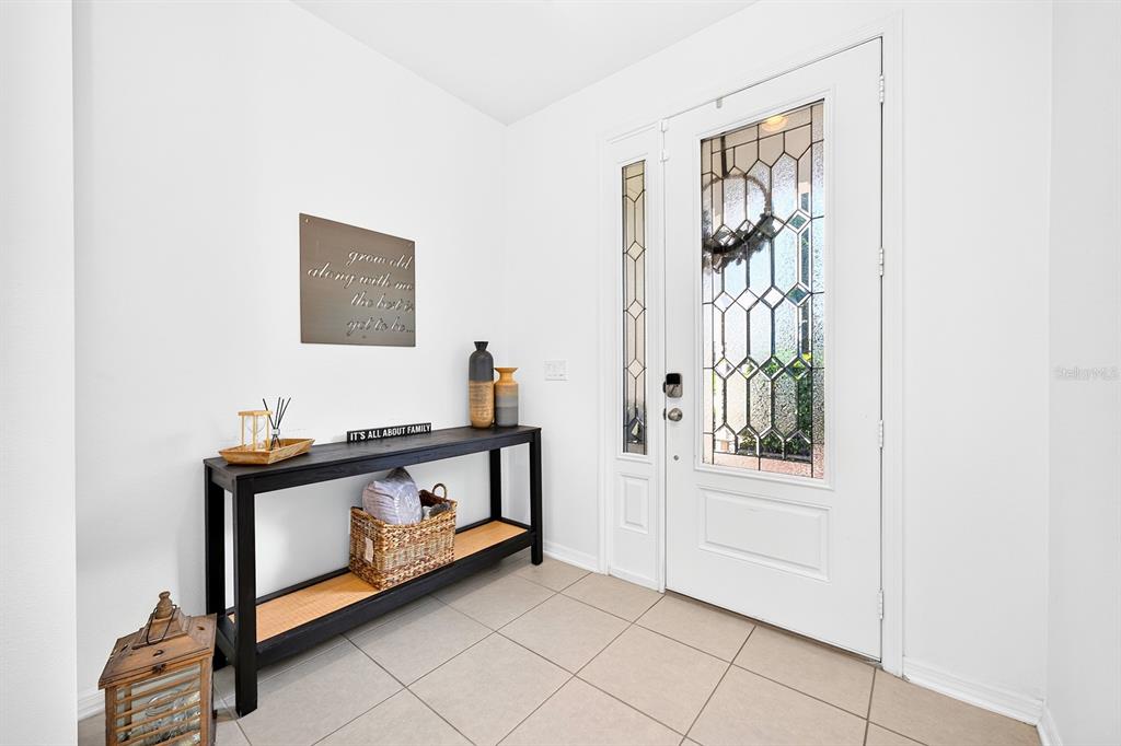 A bright entryway features a white front door with decorative glass, tile flooring, and a console — 8205 BAYLISS COURT, ORLANDO, FL
