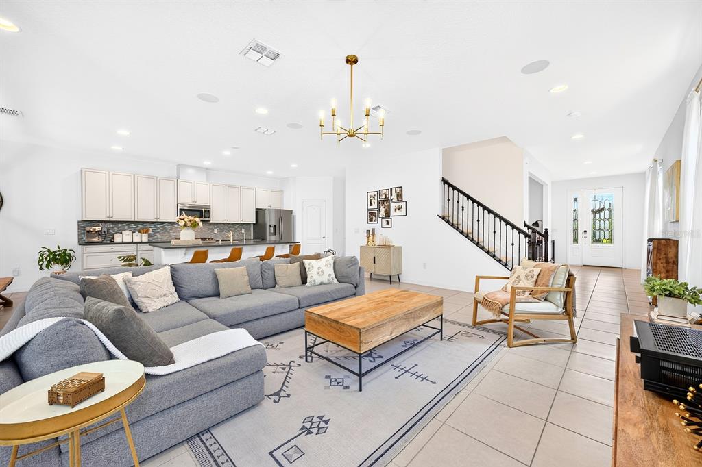 A spacious open-concept living room features a large gray sectional, wooden coffee table, and kitchen — 8205 BAYLISS COURT, ORLANDO, FL