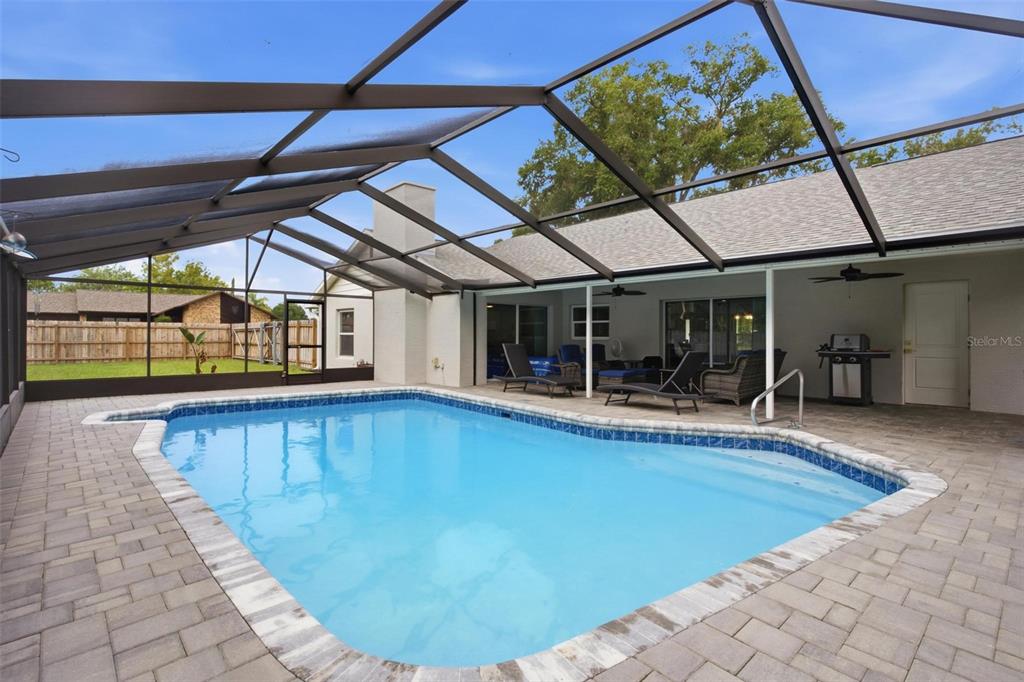 A swimming pool with a screened enclosure and paver patio sits behind a residential house — 5240 ROYAL OAK DRIVE, FRUITLAND PARK, FL