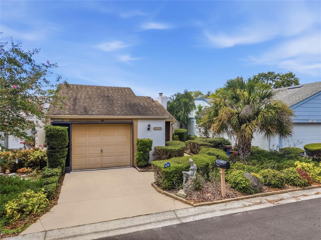 A single-story house features a tan garage door, a concrete driveway, and extensive front landscaping — 12229 CIDER MILL LANE, HUDSON, FL