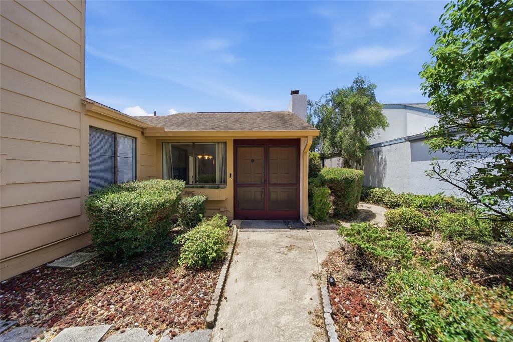 A concrete walkway leads to the front entrance of a house with tan siding — 12229 CIDER MILL LANE, HUDSON, FL