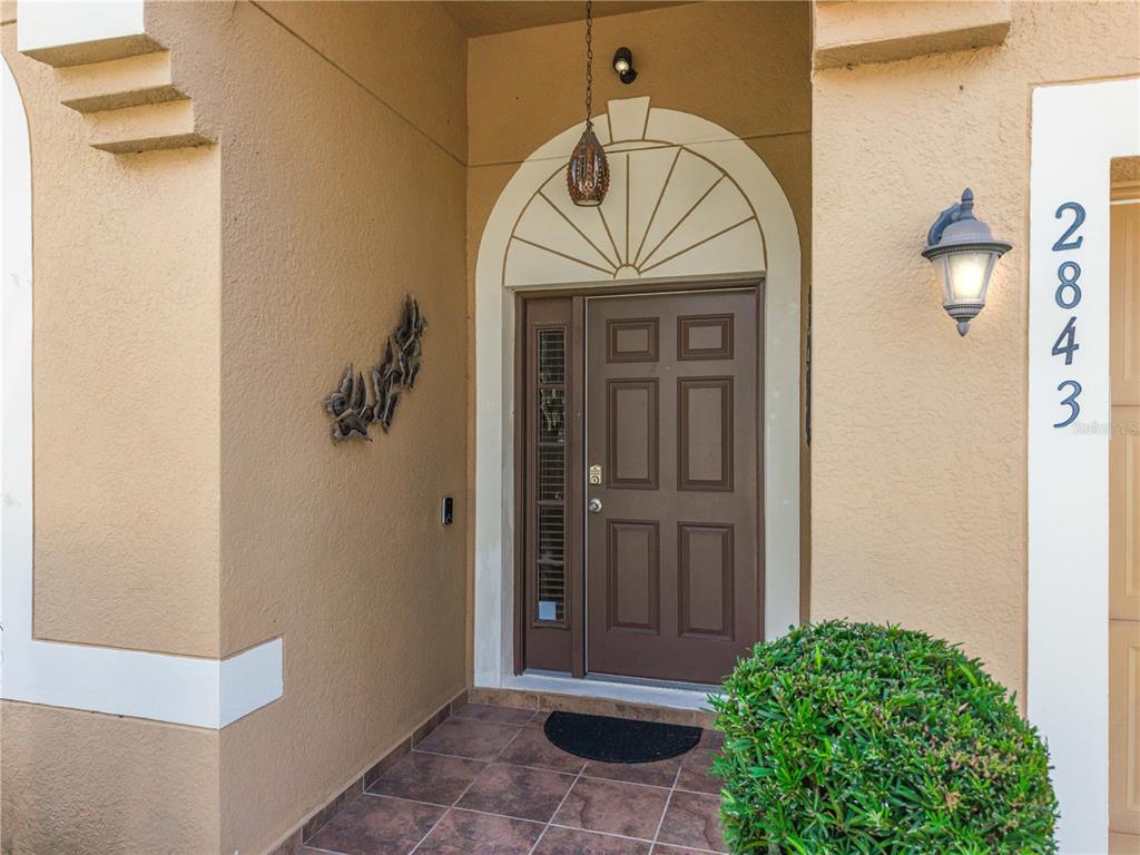 The front entrance features a brown door with a side light and arched transom window — 2843 JASPER RUN, KISSIMMEE, FL