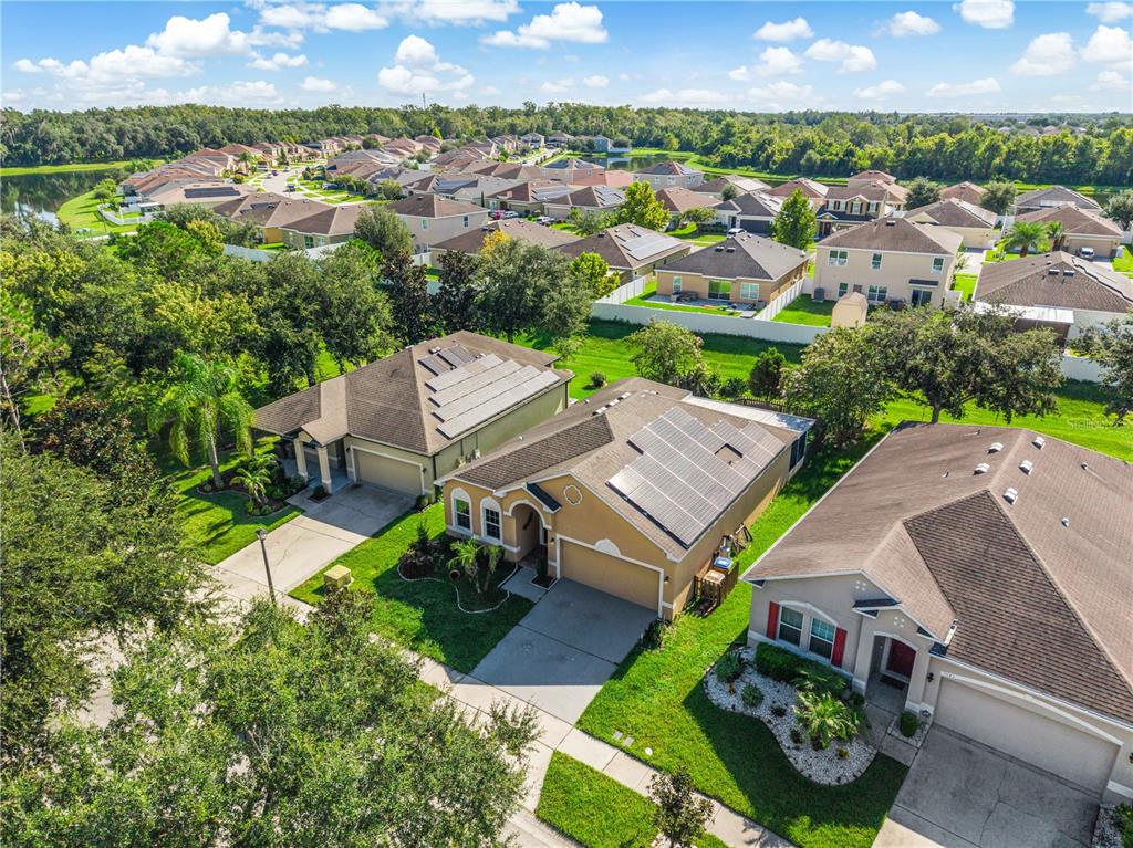 An aerial view shows suburban houses with solar panels on their roofs and green lawns — 2843 JASPER RUN, KISSIMMEE, FL