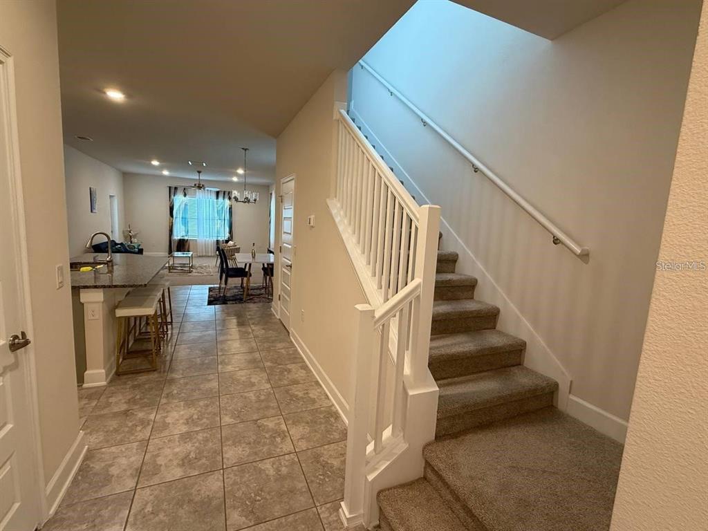 A tiled entryway leads to a kitchen with a breakfast bar and a carpeted staircase — 3828 SAGEFIELD DRIVE, HARMONY, FL