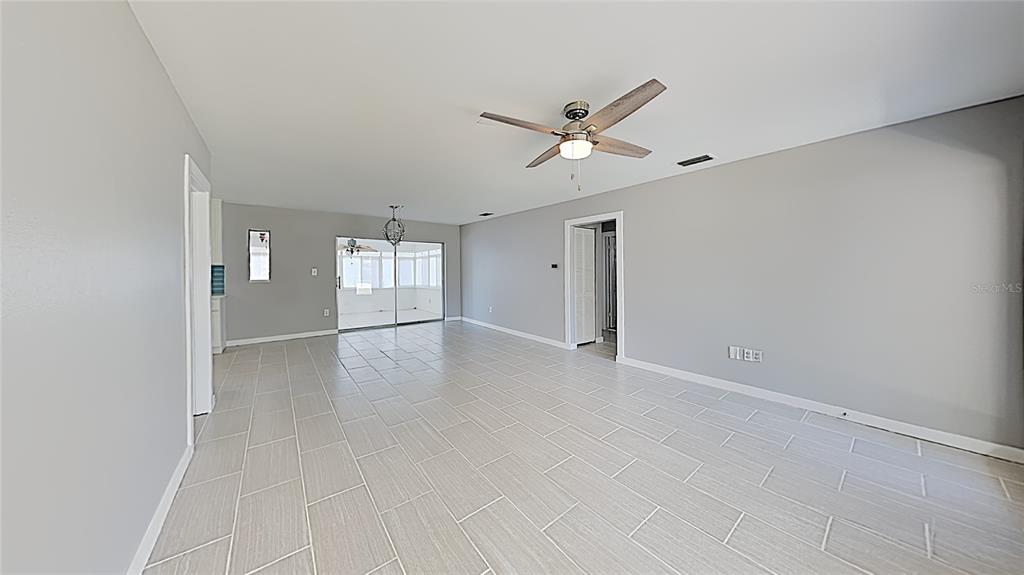 A spacious living area features light gray walls, large tile flooring, and a ceiling fan — 4511 S GAINES ROAD, TAMPA, FL
