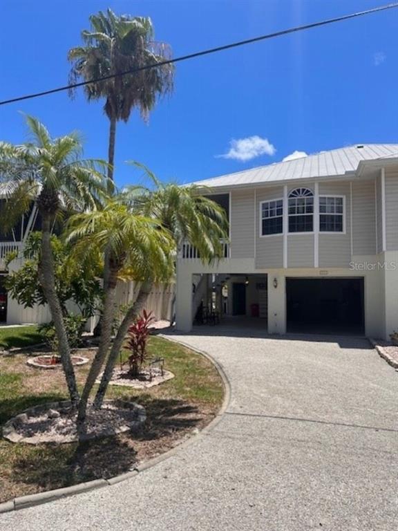 A two-story house with a raised living area, a ground-level garage, and palm trees — 1811 HIGHLAND ROAD, OSPREY, FL