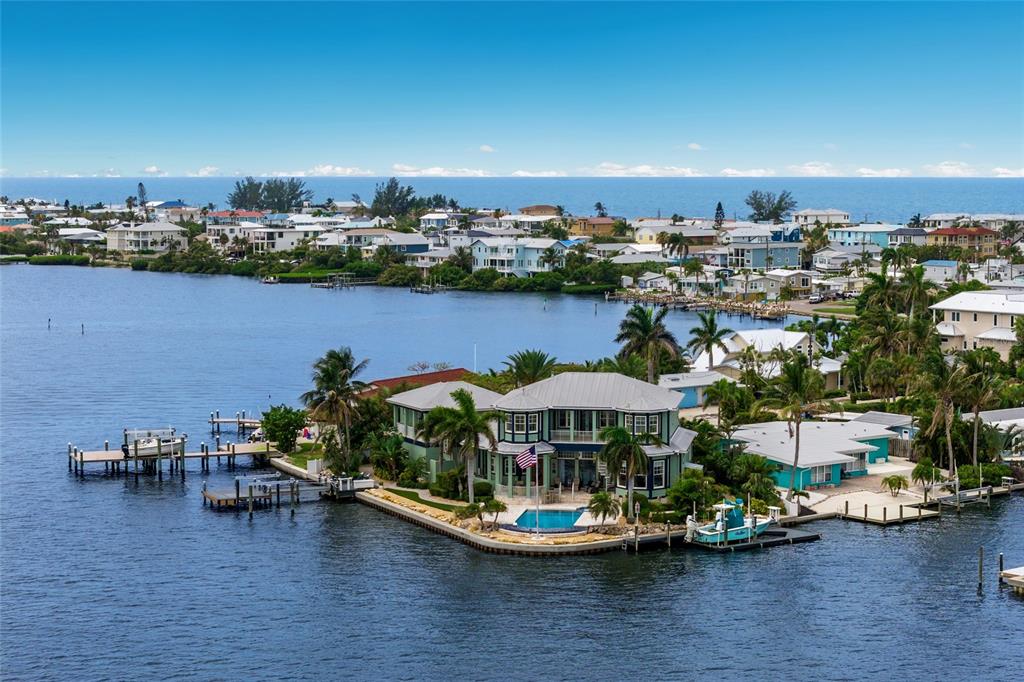 An aerial view of a waterfront house with a pool, dock, and American flag — 522 BAYVIEW DRIVE, HOLMES BEACH, FL