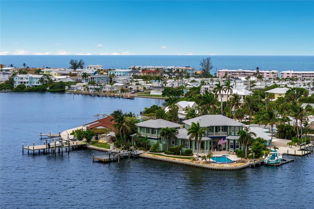 An aerial view shows a waterfront house with a pool, docks, and surrounding coastal homes — 522 BAYVIEW DRIVE, HOLMES BEACH, FL
