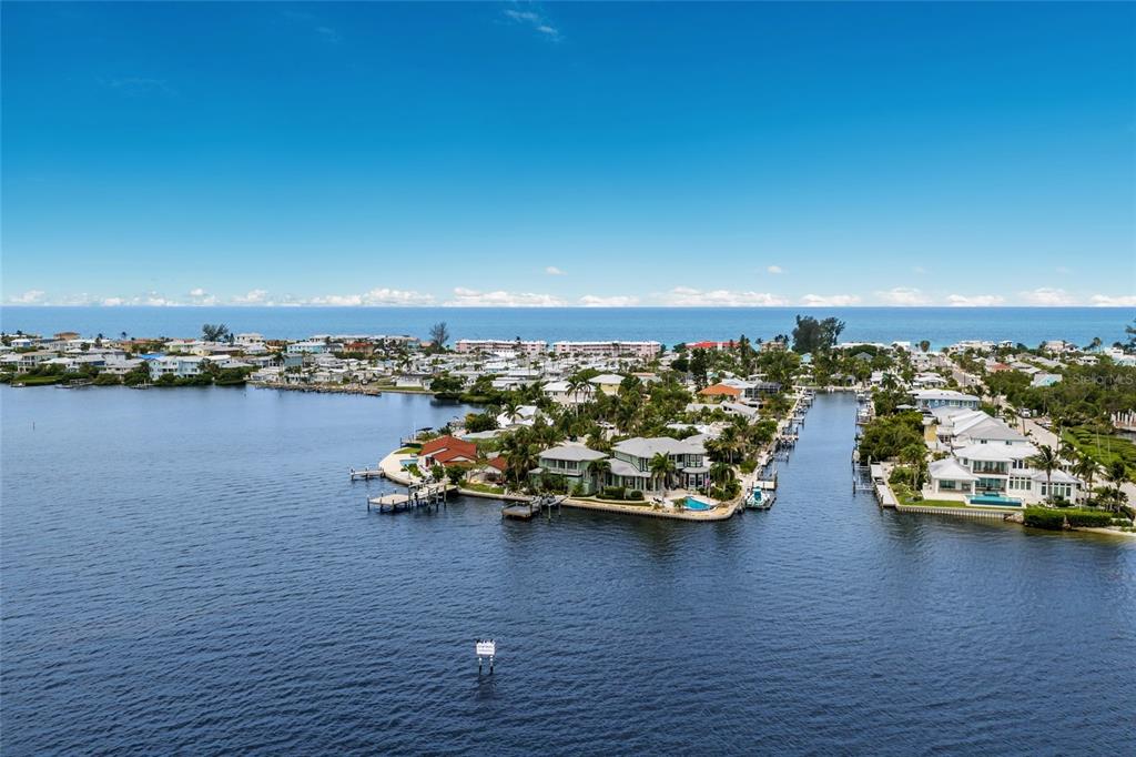 An aerial view shows waterfront homes along a canal leading to the open ocean — 522 BAYVIEW DRIVE, HOLMES BEACH, FL