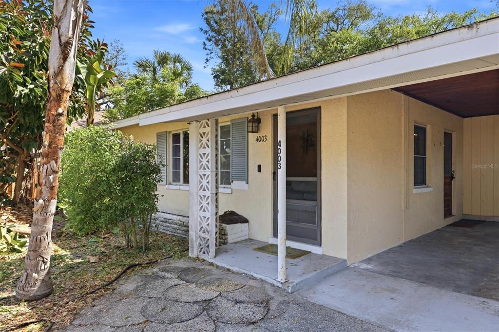 A single-story house with a yellow stucco exterior, a carport, and a decorative concrete pillar — 4003 BOOTH PLACE, SARASOTA, FL