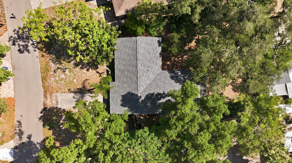 An aerial view shows an L-shaped house with a gray shingled roof surrounded by trees — 4003 BOOTH PLACE, SARASOTA, FL