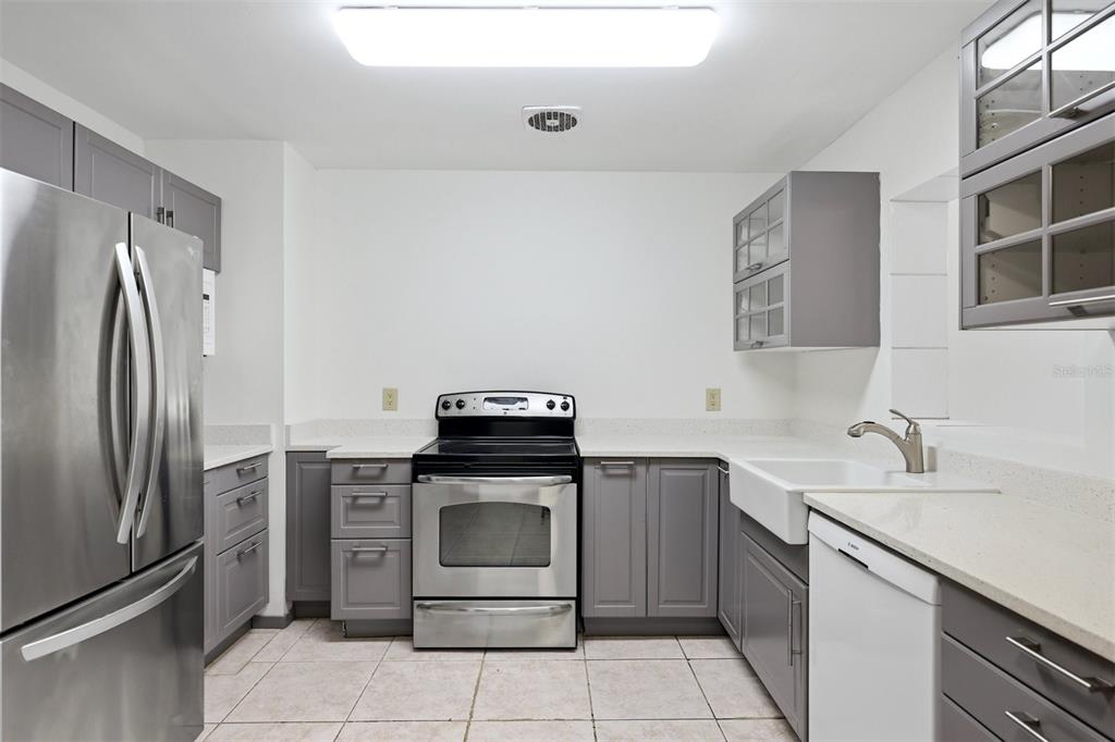 A kitchen features gray cabinets, stainless steel appliances, a farmhouse sink, and white countertops — 4003 BOOTH PLACE, SARASOTA, FL
