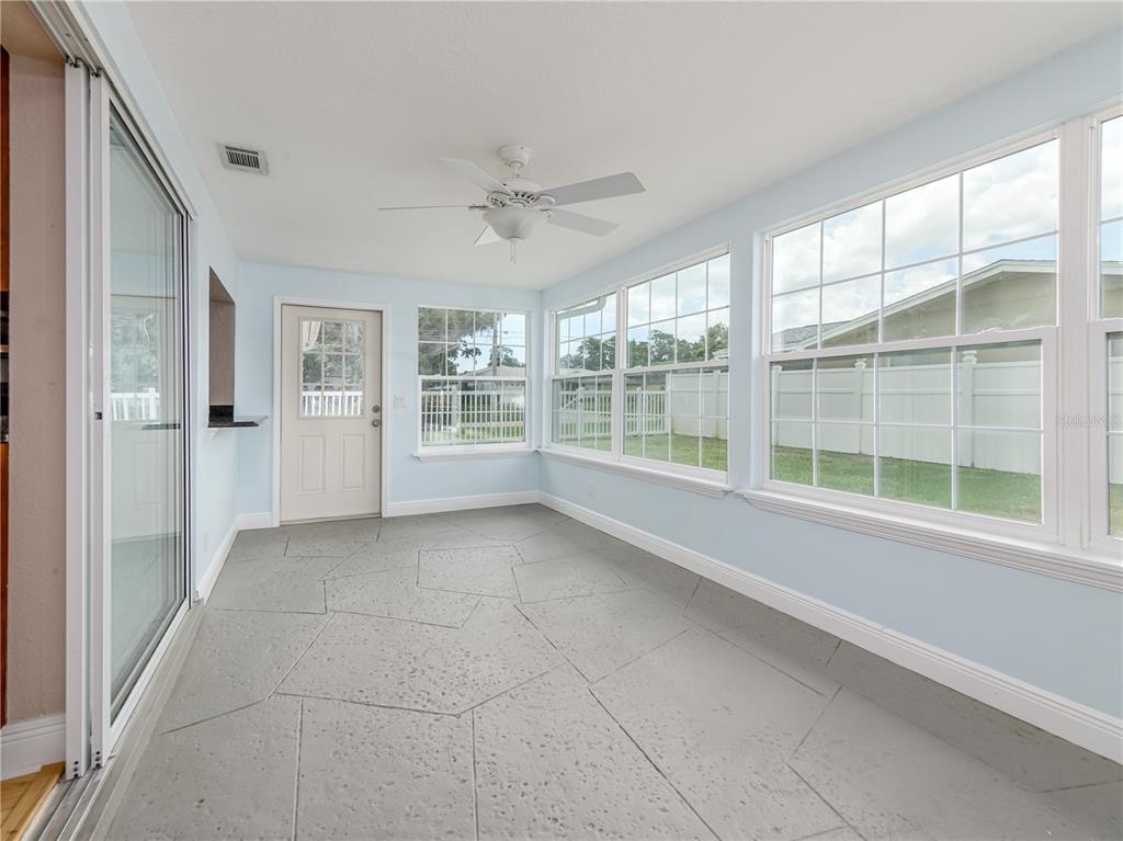 A sunroom with light blue walls, a ceiling fan, and gray stone-patterned flooring — 1661 ALGONQUIN DRIVE, CLEARWATER, FL